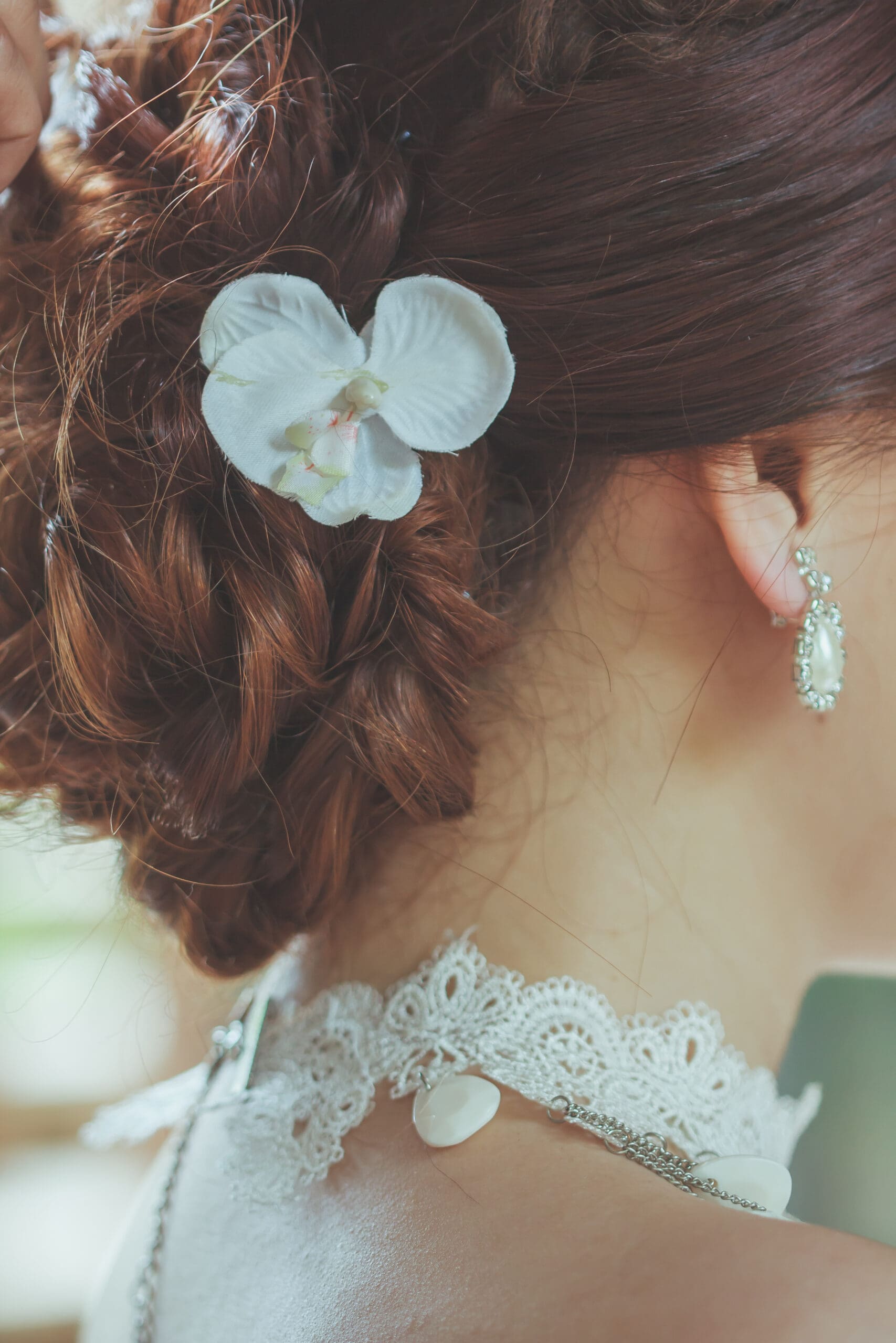 2. Floral and Hair Clips: Whimsical and Modern Floral hair clips and decorative pieces have become a popular, modern alternative to traditional veils. They bring a whimsical, personalized touch to the bridal look. Floral Crowns: Ideal for boho or rustic weddings, floral crowns add a soft, romantic vibe using fresh blooms or silk flowers. Hair Clips and Combs: Embellished with pearls, crystals, or detailed designs, these can add just the right amount of sparkle without overpowering your hairstyle. Why It’s Popular: These accessories are incredibly versatile. They can be customized to fit your color palette and wedding theme while showcasing your personality and style. 3. Short Veil: Sweet and Stylish Short veils, like birdcage and blusher styles, offer a sweet, stylish option for brides looking for something less traditional and more low-maintenance. Birdcage Veil: A vintage-inspired piece that partially covers the face, often paired with an elegant updo or retro-inspired gown. Blusher Veil: A single-layer veil worn over the face and lifted by the groom — adding a moment of tradition with a modern twist. Why It’s Popular: Short veils complement the dress without overwhelming it. They’re perfect for vintage, city, or casual weddings where ease and elegance go hand-in-hand. Close-up of a bridal updo featuring a white flower hair pin