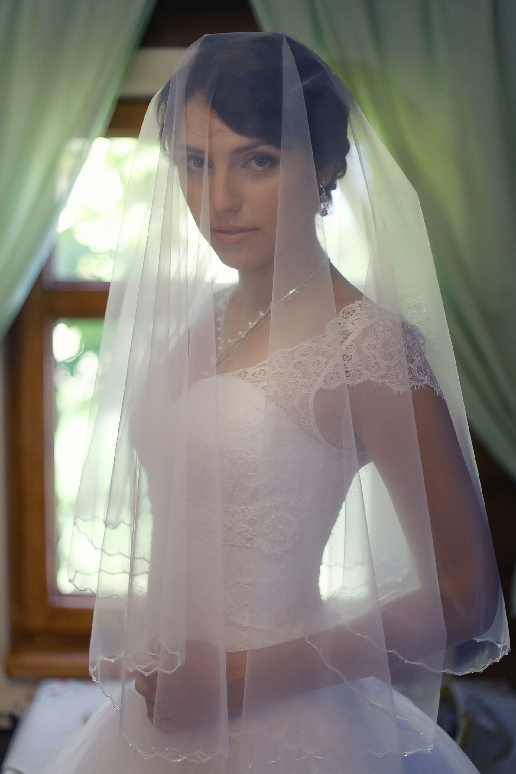 Bride wearing short veil indoors Bride standing indoors wearing a short, sheer wedding veil over her face