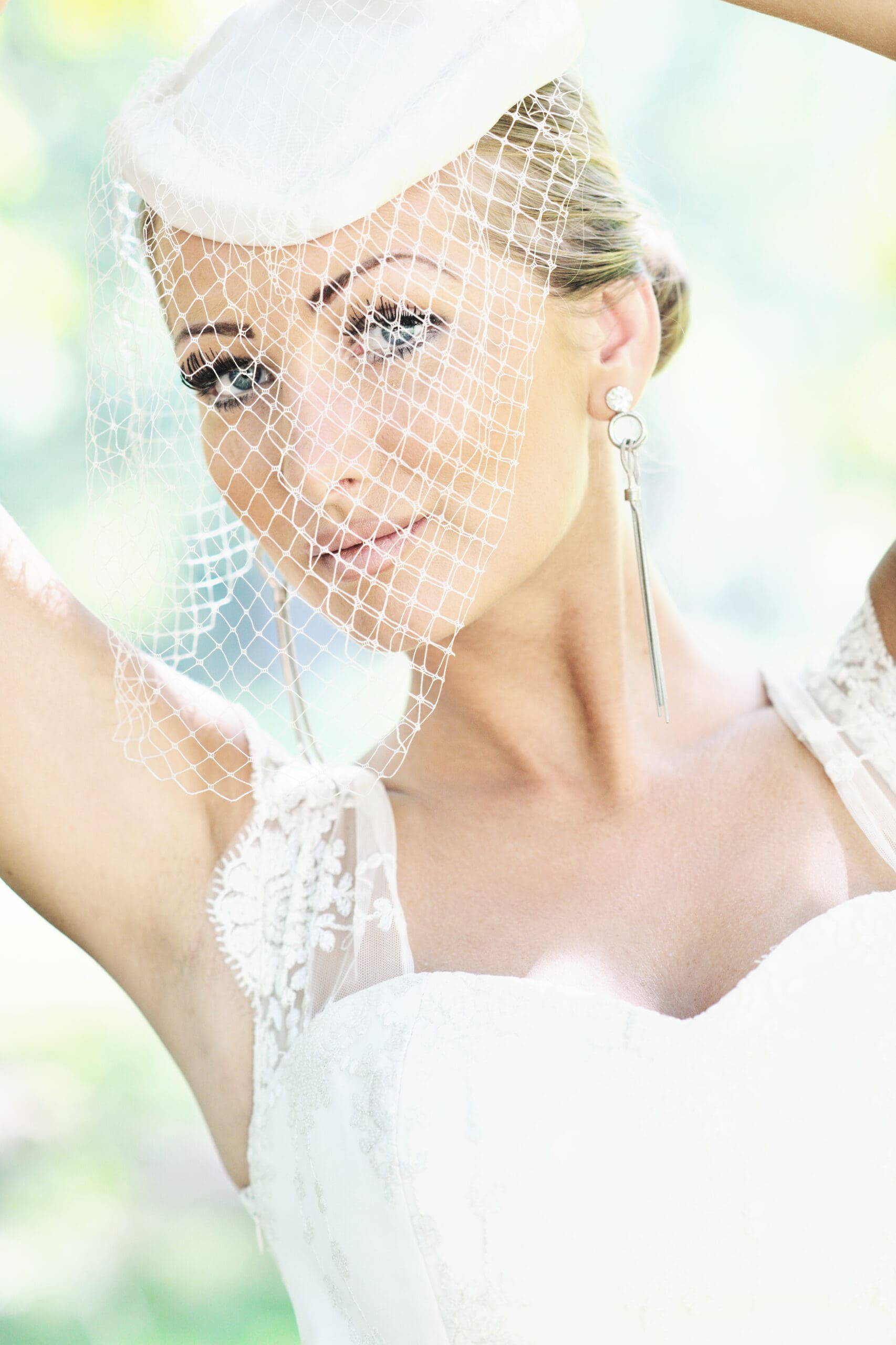 Bride Wearing Fascinator with Birdcage Veil Bride wearing a white fascinator with birdcage netting, styled in a soft bridal updo