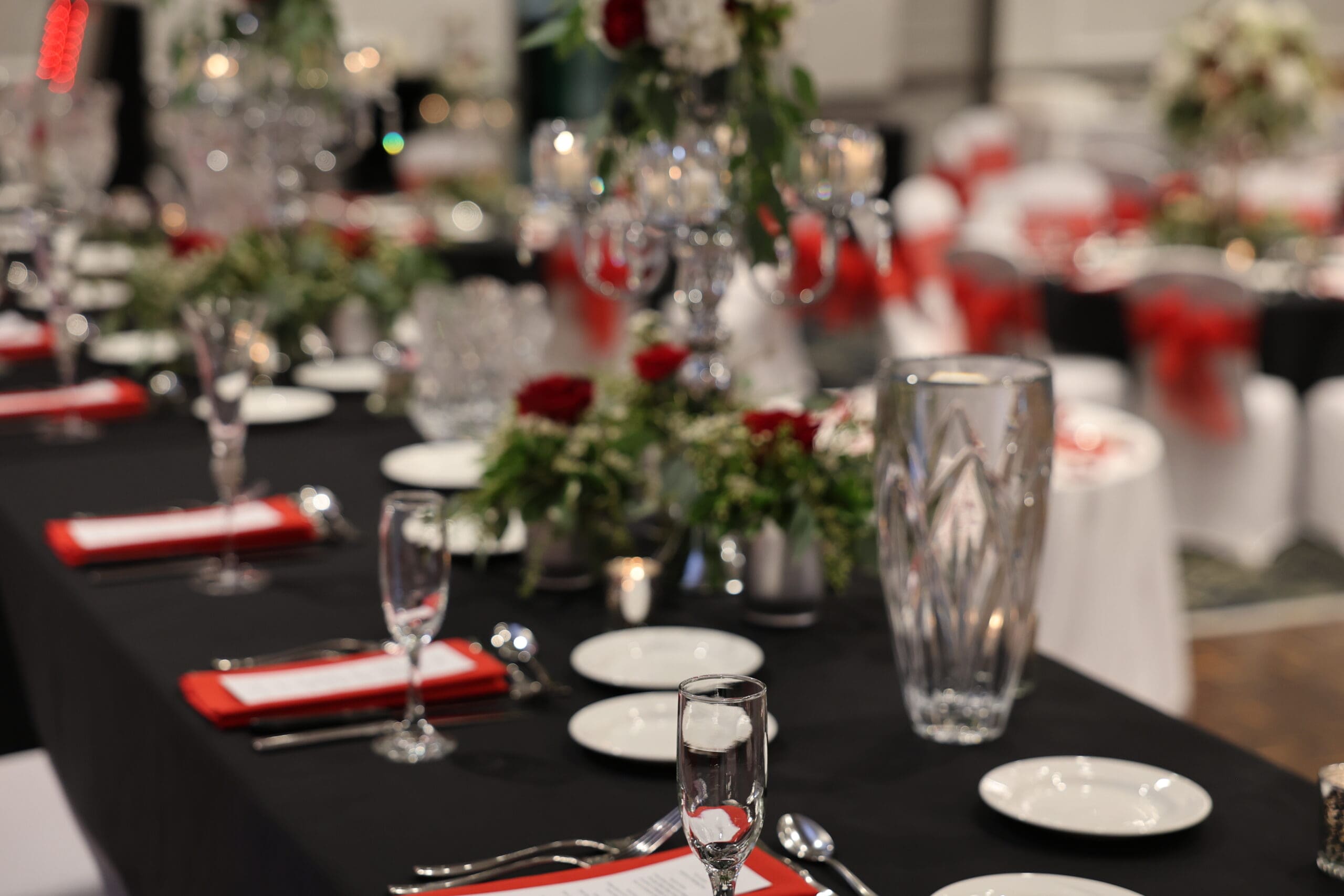 Elegant Pittsburgh wedding reception table with black linens, red napkins, crystal glassware, and red and white floral centerpieces.